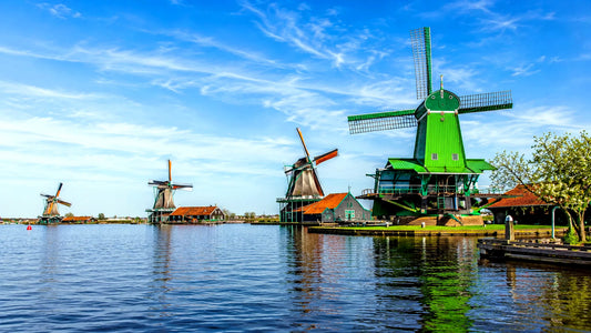 Breedbeeldfoto van de iconische Zaanse Schans met traditionele groene windmolens aan het water in Zaanstad, Nederland – sfeervolle 8K landmarkfoto voor meubels herstofferen en meubelstoffering in Zaanstad.